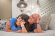 © luciano - Happy relaxed senior couple of retired lying in bed looking at camera. Smiling elderly man and woman enjoying cuddle moments
