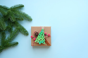 Wall Mural - decorated gift box with Christmas tree, fir tree branches on blue background. Christmas and New Year holidays concept. winter festive season. flat lay. copy space. element for design