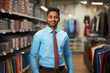 © Niks Ads - Young indian salesman standing at clothing store.