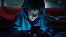 Small Boy Watching Tablet Or Mobile Phone At Bed, Blanket Over His Head. Bedtime Harmful Blue Light Screentime Concept
