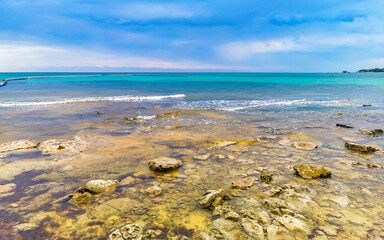 Wall Mural - Stones rocks corals turquoise green blue water on beach Mexico.