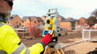 © Iryna - Surveyor builder site engineer with theodolite total station at construction site outdoors during surveying work