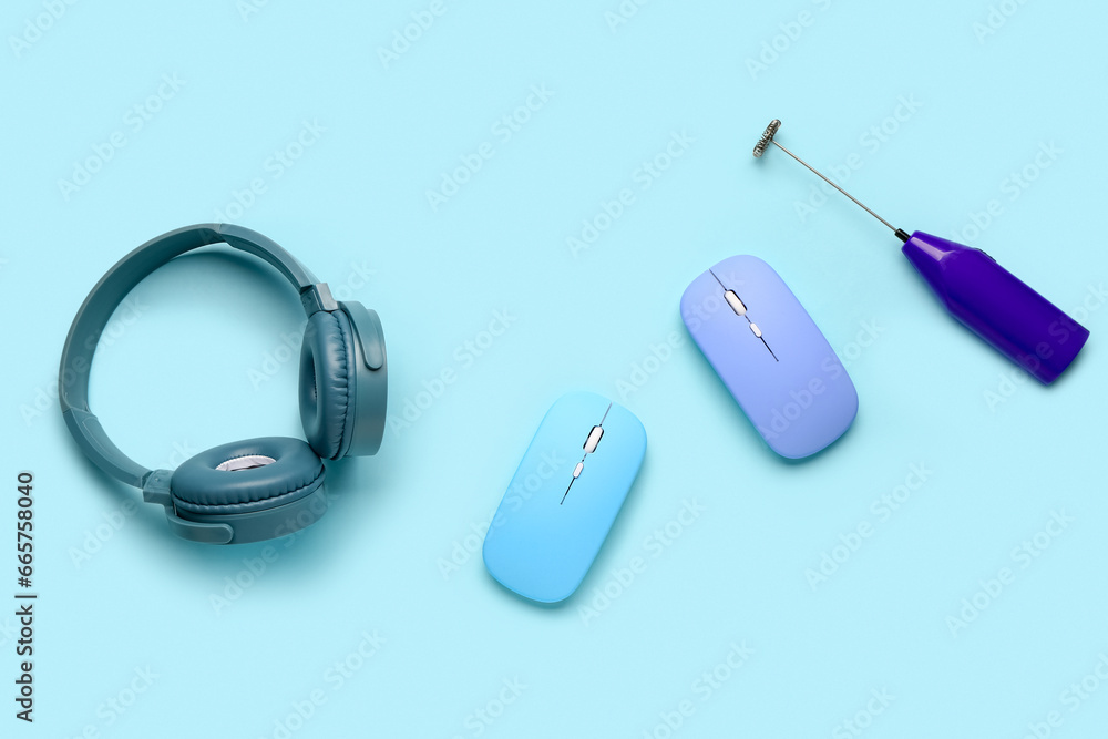 Modern headphones with computer mouses and mixer on blue background