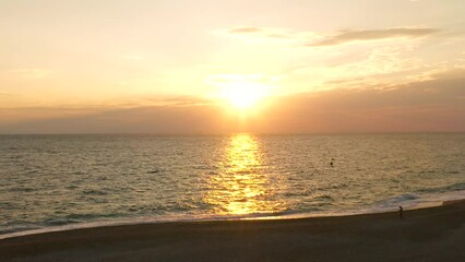 Wall Mural - Sunrise on a Greek island beach, with calm waves breaking at first light