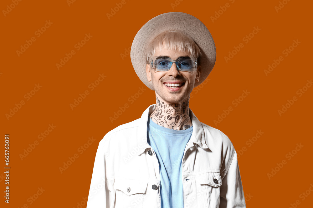 Young tattooed man in stylish sunglasses on color background