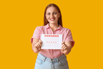 Wall Mural - Young woman with menstrual calendar on yellow background