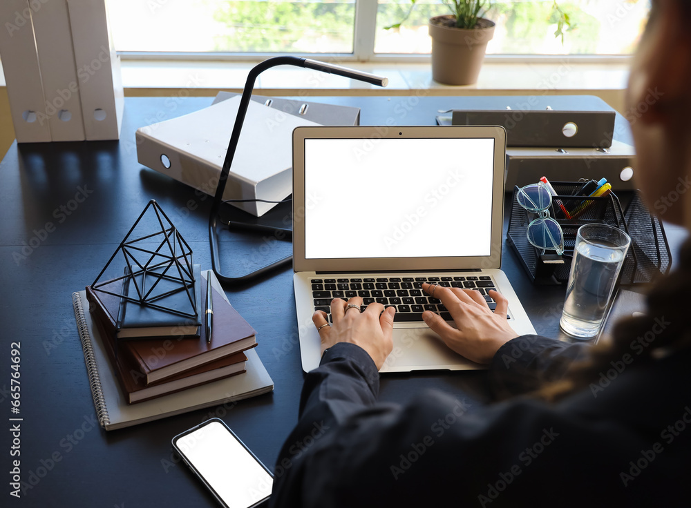 Woman using laptop at table in office, closeup