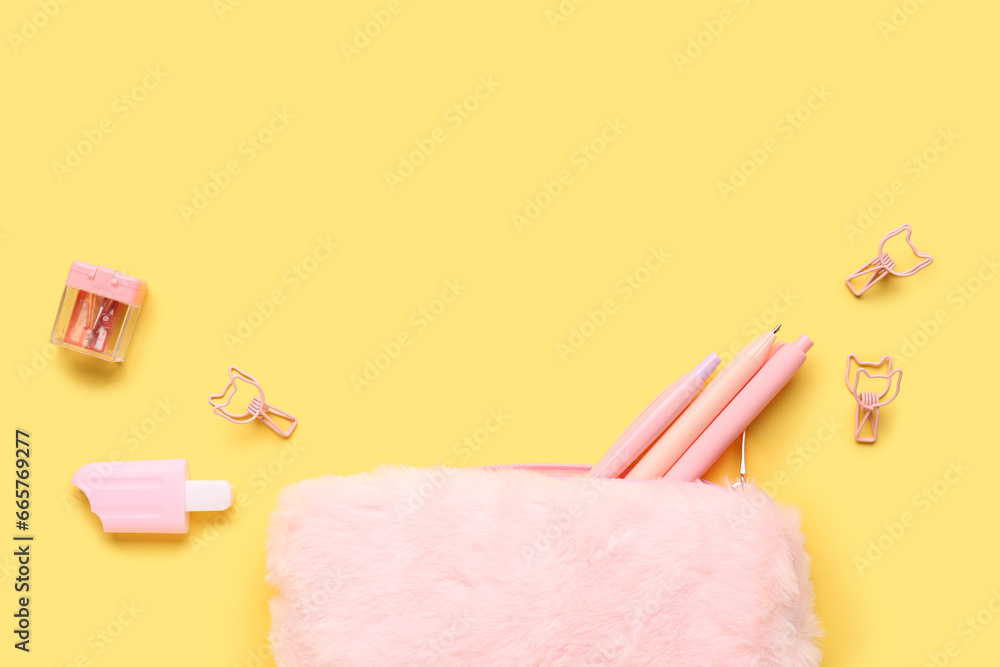 Pink pencil case with school stationery on yellow background