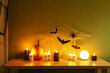 Table with burning candles and Halloween decor in dark room