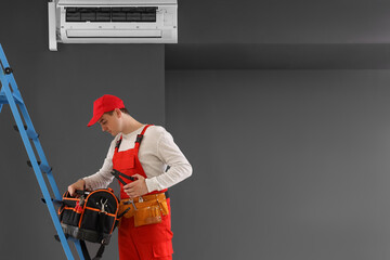 Poster - Male technician taking tools to fix air conditioner in room