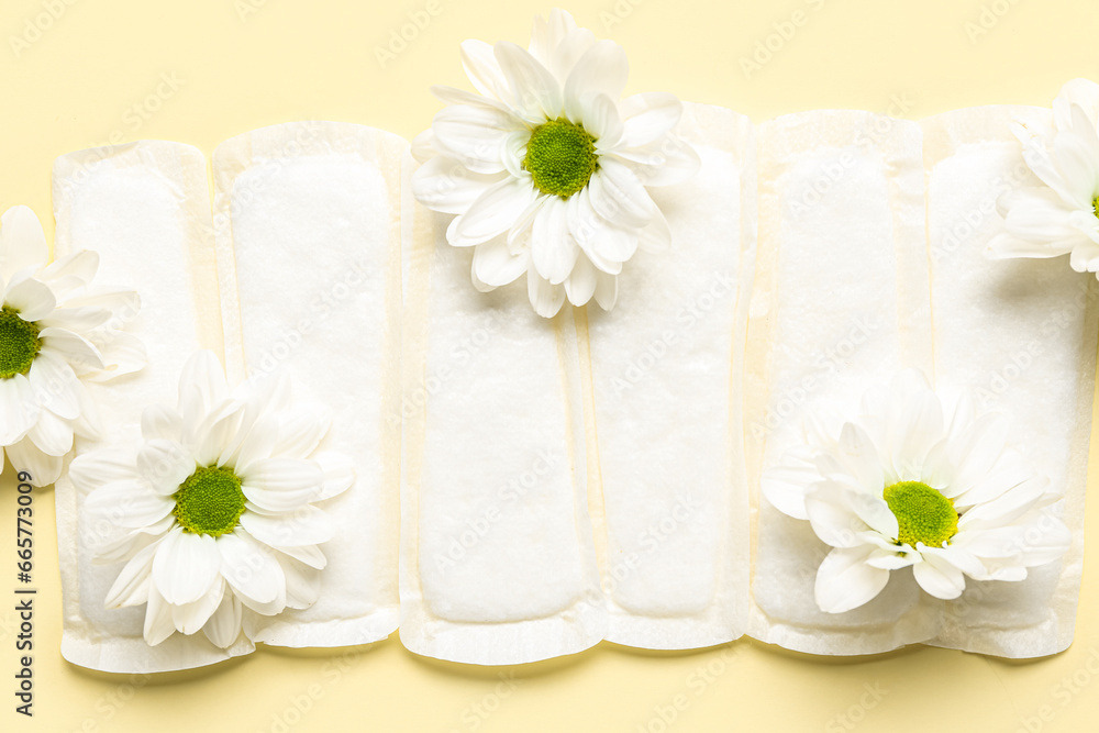 Composition with menstrual pads and beautiful chamomile flowers on color background, closeup