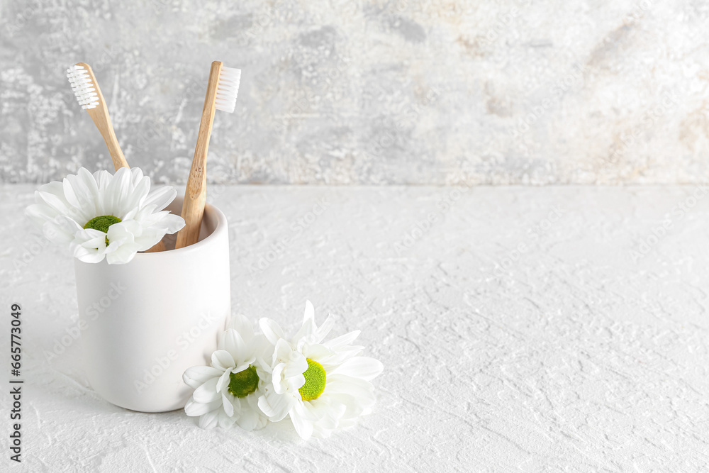 Holder with toothbrushes and chamomile flowers on table