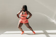 © gstockstudio - Full length of happy African plus size woman in sportswear warming up before training