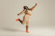 © gstockstudio - Full length happy plus size African woman in sportswear dancing on studio background
