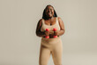 © gstockstudio - Happy plus size African woman in sportswear exercising with dumbbells on studio background