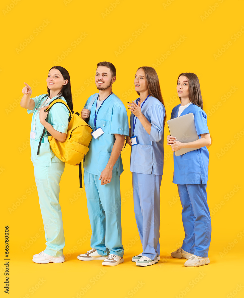 Group of medical students pointing at something on yellow background