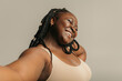 © gstockstudio - Joyful plus size African woman in sportswear making selfie while standing on studio background