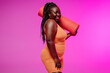 © gstockstudio - Happy plus size African woman in sportswear carrying exercise mat on pink background