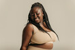 Attractive African plus size woman in underwear radiating self-love on studio background