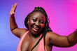© gstockstudio - Beautiful voluptuous African woman in sportswear gesturing and smiling against vibrant background