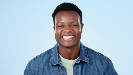 Canvas Print - Happy, wink and face of black man laughing in studio for funny, comic or good mood on blue background. Emoji, portrait and African male model with humor, comedy and positive mindset or fun attitude