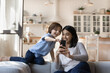 © fizkes - Happy Asian mother and Caucasian son having fun with smartphone, laughing young mom with 7s boy child looking at phone screen, watching funny video or cartoons, playing game, chatting online