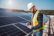 Professional engineer using digital tablet to control and use drone at work, solar cells in the background, wearing safety helmet at work