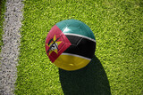 Fototapeta  - football ball with the flag of mozambique on the green field near the white line