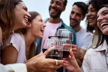 Group Multiracial Laughing Friends Toasting Glasses Red Wine And Celebrating Party Outdoors. Young People Together Cheers On Open Air. Boys And Girls Enjoying Free Time On Summer Weekend Vacation.