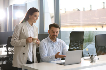 Poster - Colleagues working on laptop at desk in office