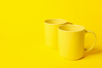 Wall Mural - Two ceramic mugs on yellow background, space for text