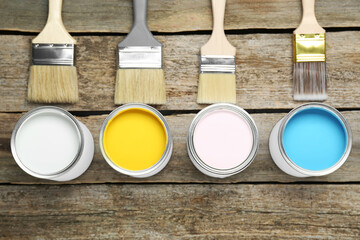 Wall Mural - Cans of colorful paints with brushes on wooden table, flat lay