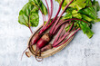 Fresh raw beets with leaves on a rustic metal dish on a gray background