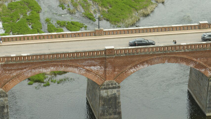 Poster - Riga, Latvia - AUGUST 20 2023.  a bridge over a river with cars driving on it and a bridge with a road going over it.