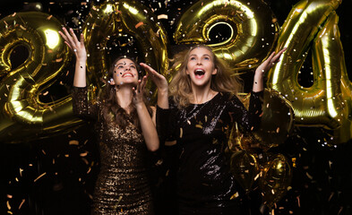 Wall Mural - Happy gorgeous girls in stylish sexy party dresses holding gold 2024 balloons, having fun at New Year's Eve Party.