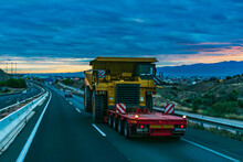 Gondola Truck For Special Transport Transporting A Dumper Truck On The Highway At Sunrise.
