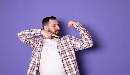 Wall Mural - Young man wearing casual white t-shirt over isolated purple background showing arms muscles. 