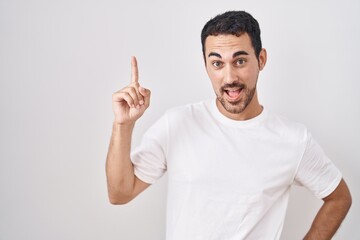 Poster - Handsome hispanic man standing over white background pointing finger up with successful idea. exited and happy. number one.