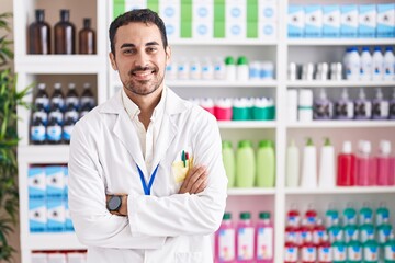 Canvas Print - Handsome hispanic man working at pharmacy drugstore happy face smiling with crossed arms looking at the camera. positive person.