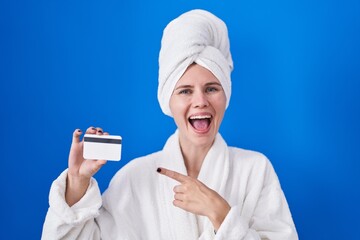 Canvas Print - Blonde caucasian woman wearing bathrobe holding credit card smiling happy pointing with hand and finger