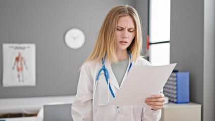 Poster - Young blonde woman doctor reading document at clinic