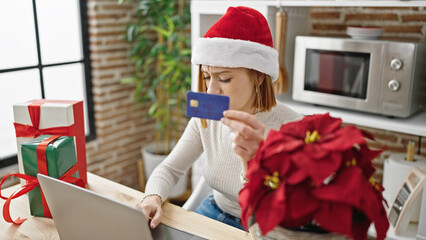 Poster - Young blonde woman shopping with laptop and credit card celebrating christmas at dinning room