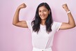 © Krakenimages.com - Young hispanic woman standing over pink background showing arms muscles smiling proud. fitness concept.