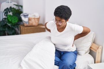 Canvas Print - African american woman suffering for knee injury sitting on bed at bedroom