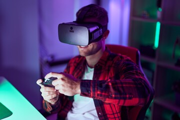 Poster - Young caucasian man streamer playing video game using virtual reality glasses and joystick at gaming room