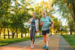 Beautiful sporty healthy active cheerful smiling middle-aged couple going to workout outdoors in park holding mats for yoga, pilates, gym. Sports healthy lifestyle. Friends on a morning walk.