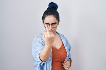 Wall Mural - Young modern girl with blue hair standing over white background showing middle finger, impolite and rude fuck off expression