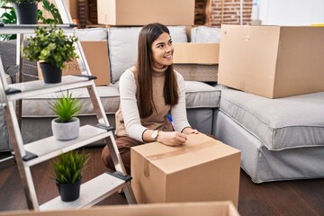 Poster - Young beautiful hispanic woman smiling confident writing on package at new home