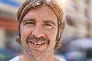 Wall Mural - Young blond man smiling confident standing at street