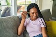 © Krakenimages.com - African american woman listening audio message by smartphone sitting on sofa at home